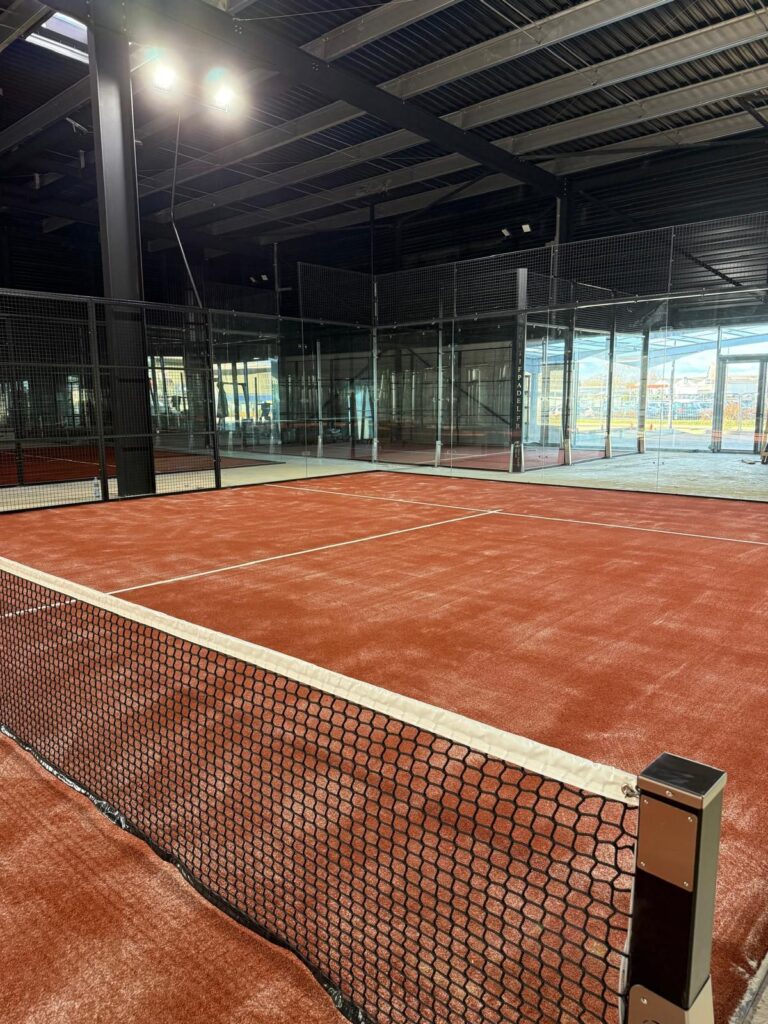 Court de padel indoor ouvert sur les baies vitrées et le parking, Cocoon Padel Club Rouen