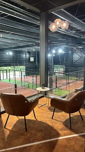 Fauteuils lounge donnant sur les terrains de padel indoor du Cocoon Padel Club a Rouen