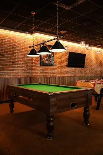Table de billard verte sous éclairage suspendu dans l'espace jeux du Cocoon Padel Club