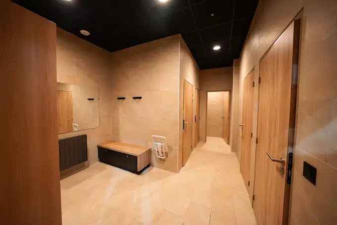 Vestiaire spacieux avec banc et casiers bois au club de padel près de Rouen