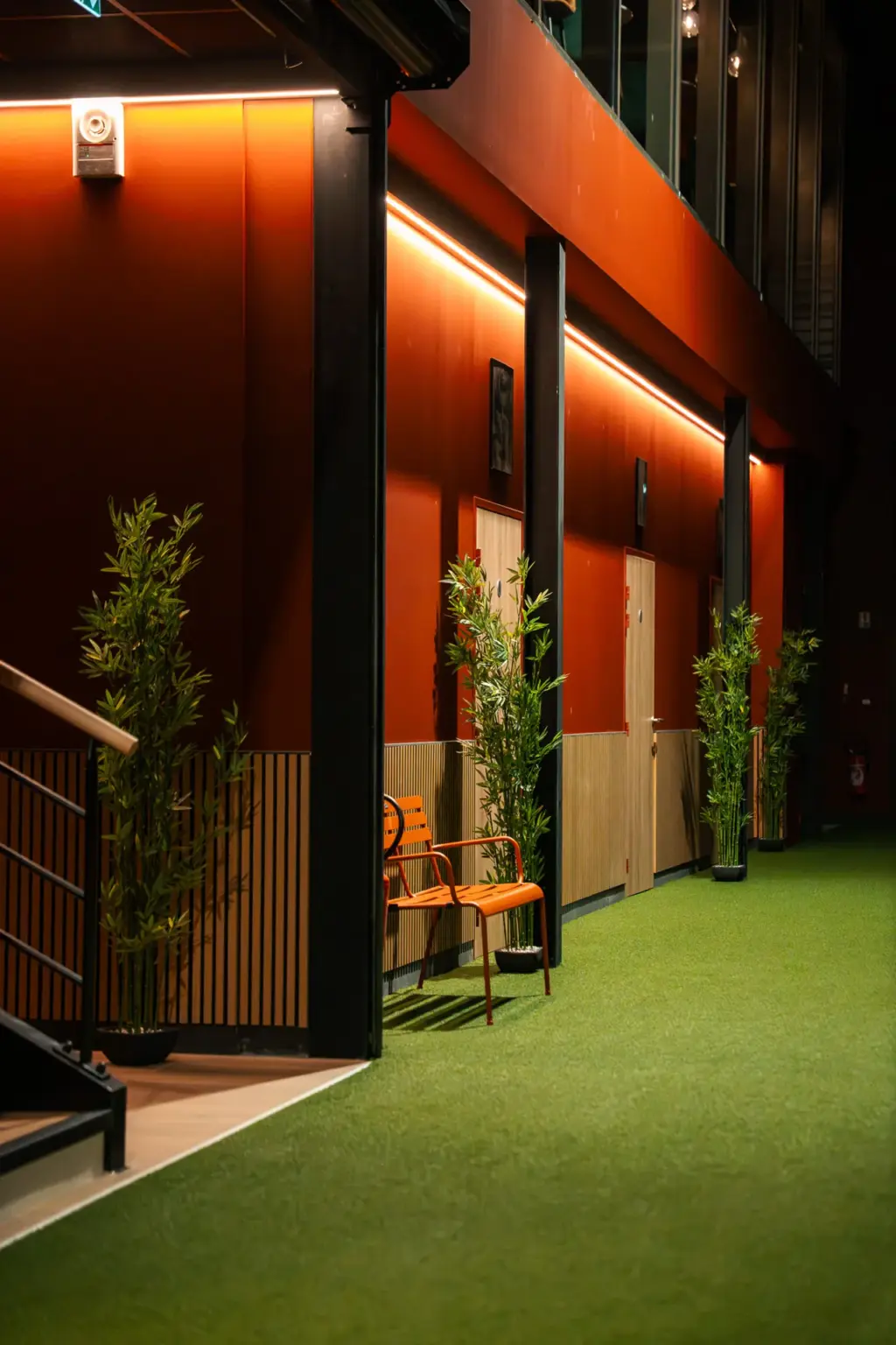 Allée en gazon avec chaise orange et bambous près de l'escalier du club de padel à Rouen