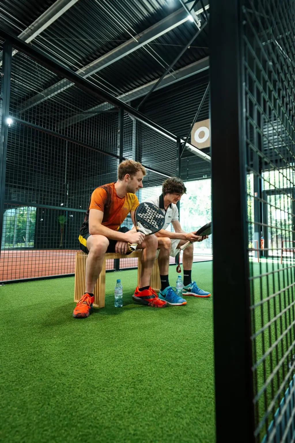 Deux joueurs assis échangeant autour de leurs raquettes au Cocoon Padel Club