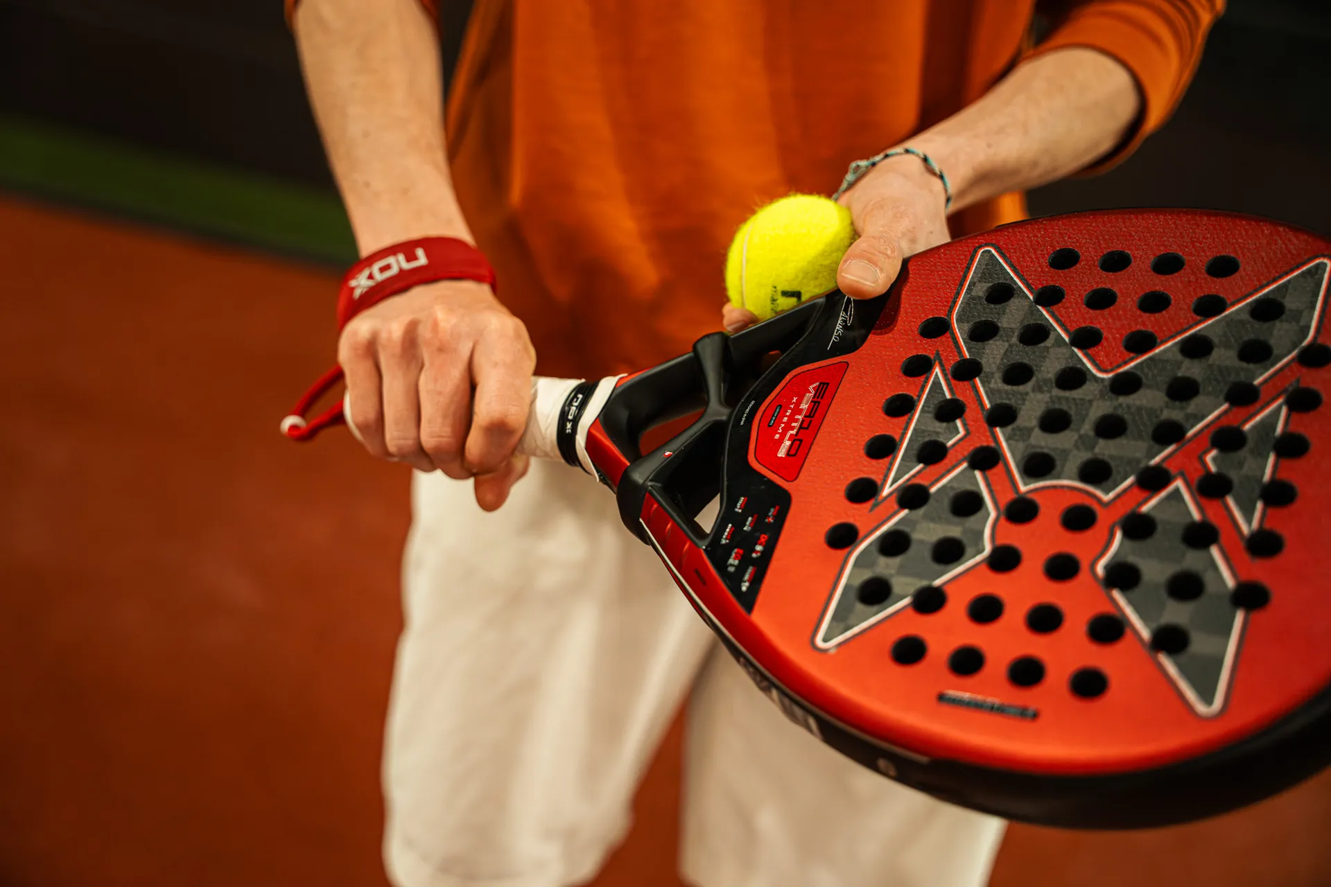Joueur tient une raquette de padel NOX rouge et une balle jaune sur le terrain, Cocoon Padel Club à Rouen