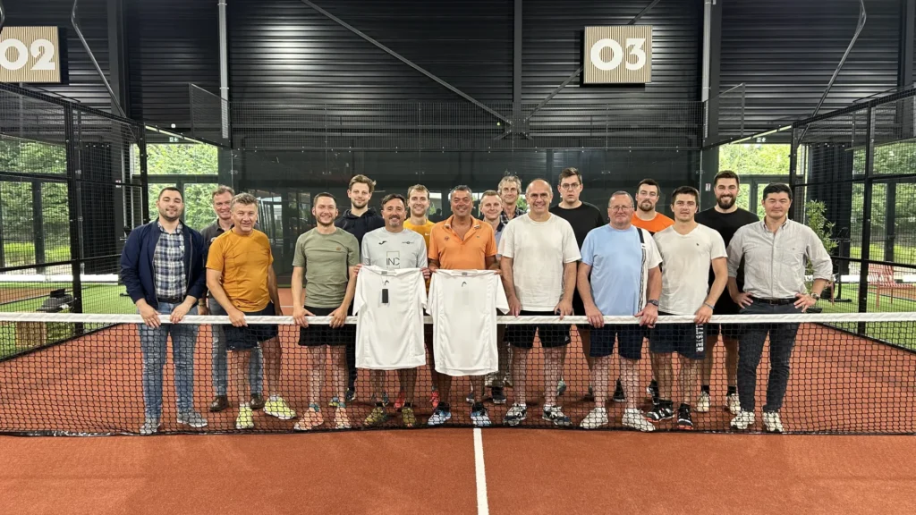 Participants d'un tournoi de padel réunis autour du filet sur un terrain indoor du Cocoon Padel Club