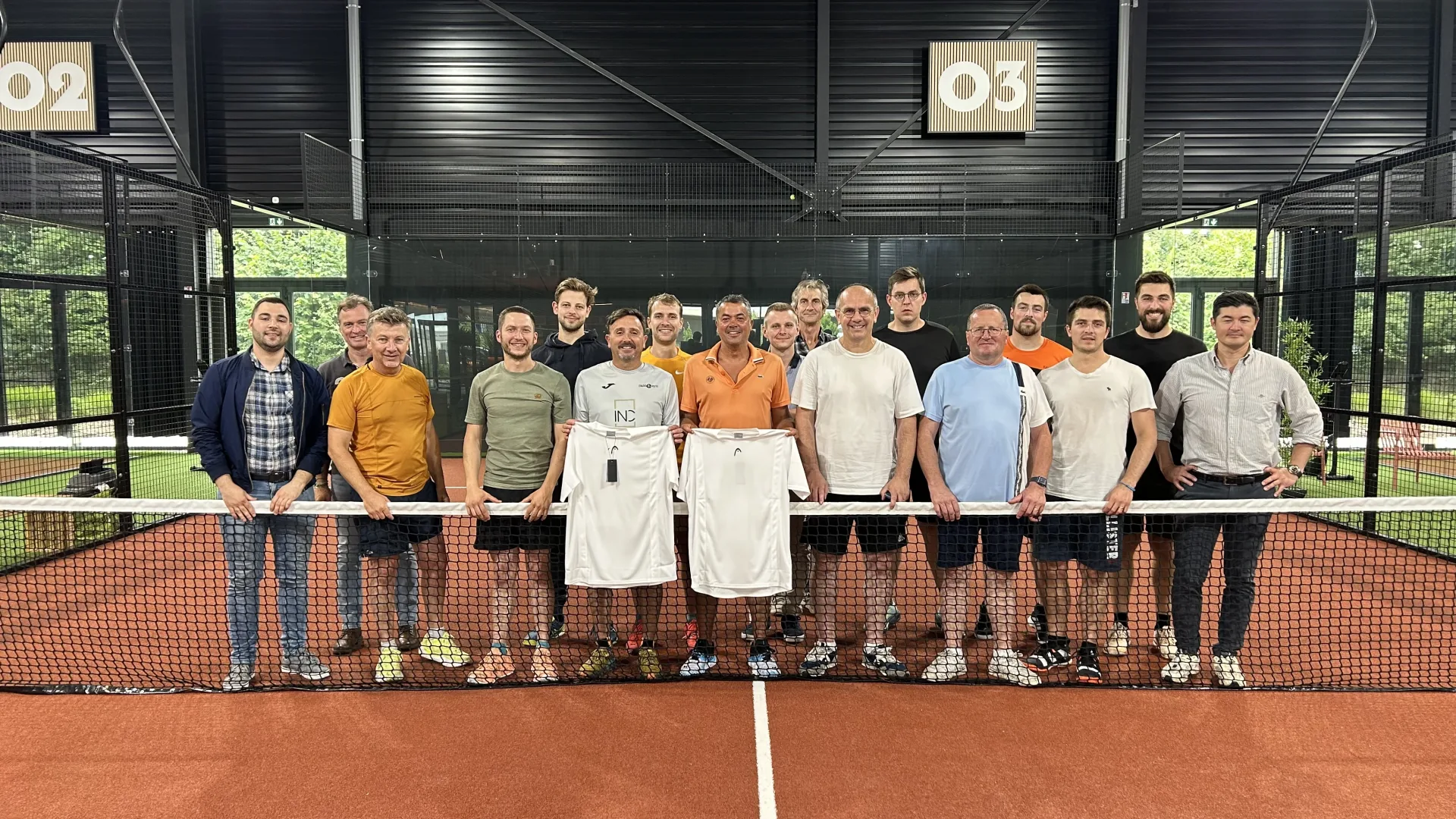 Participants d'un tournoi de padel réunis autour du filet sur un terrain indoor du Cocoon Padel Club